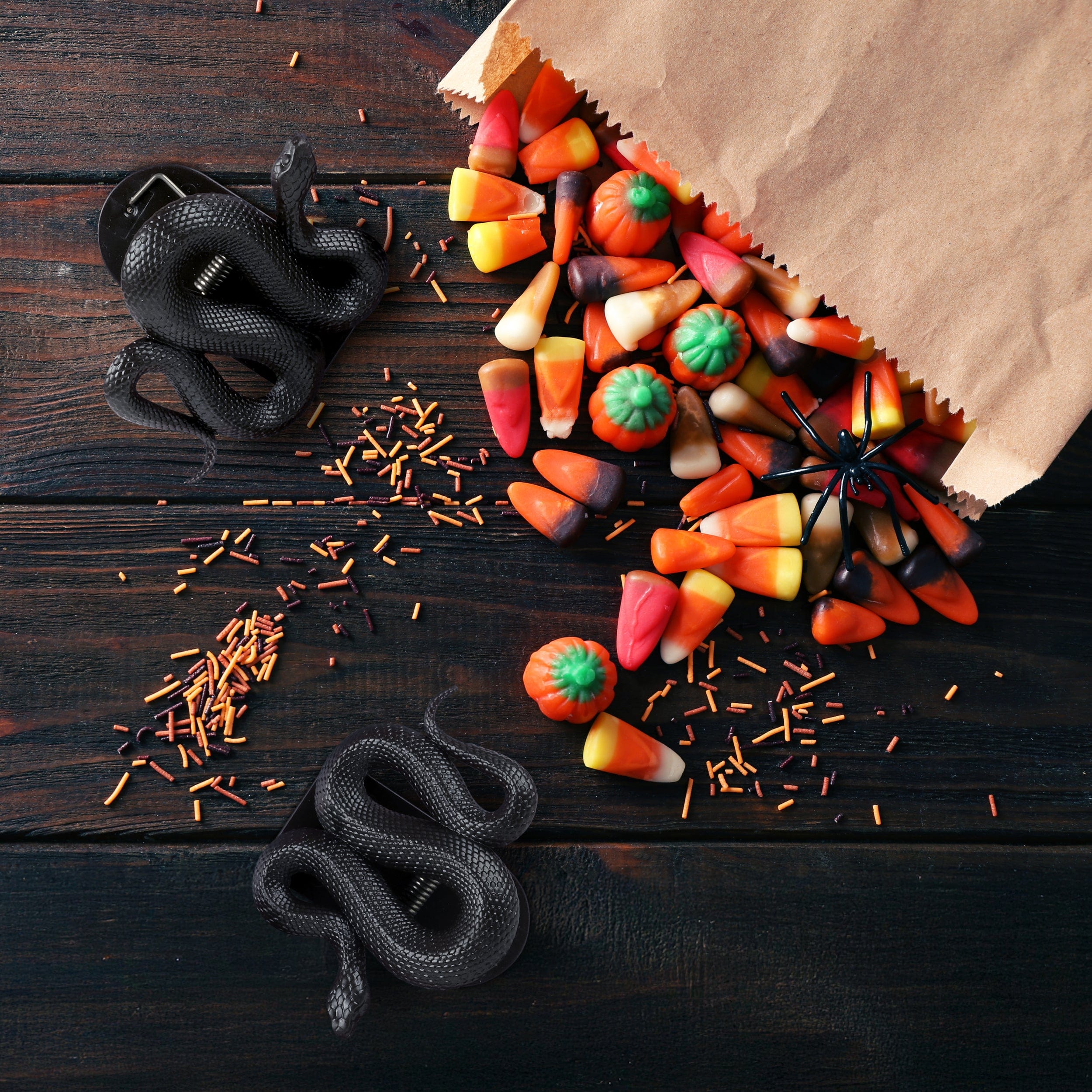 Halloween-themed candy arrangement on a wooden surface with black snake bag clips