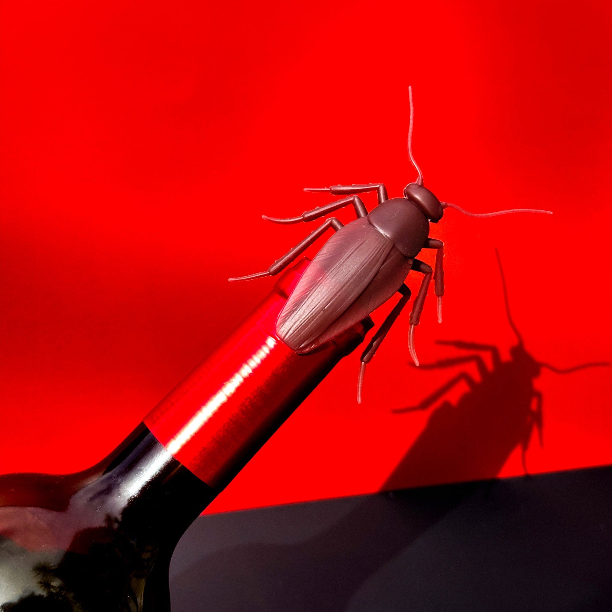cockroach bottle stopper on a bottle against a red background