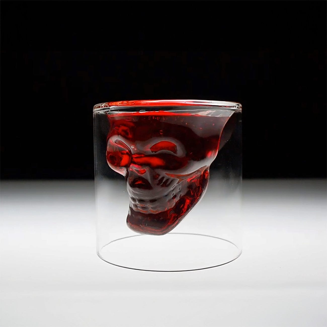 Glass with a skull design filled with red liquid on a black and white background