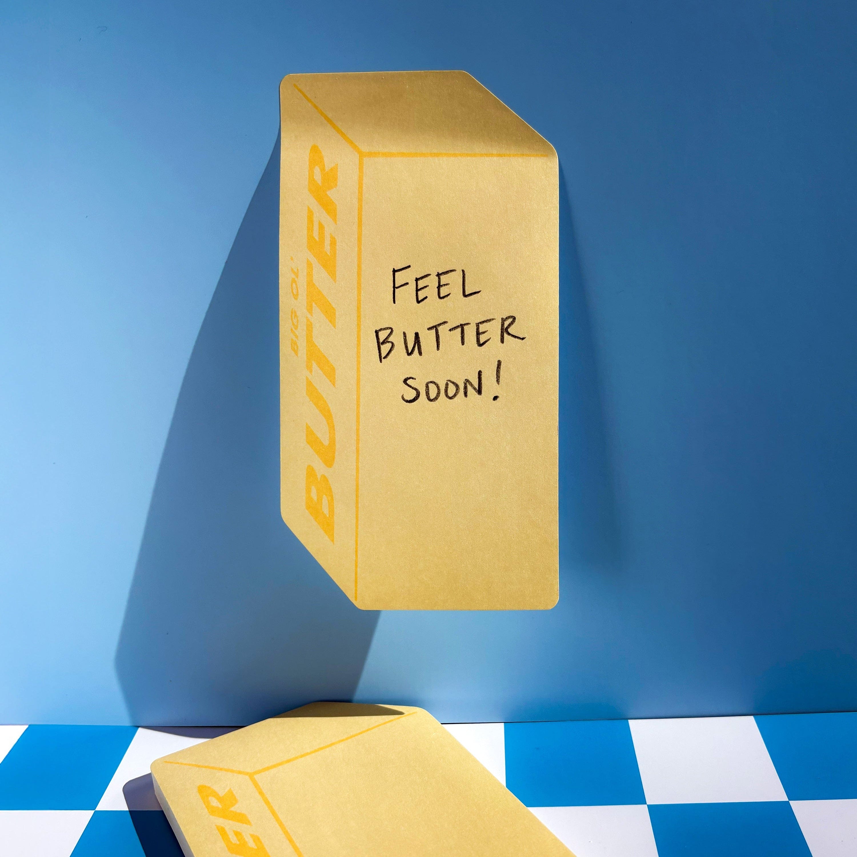 Stick of Butter Sticky Notes with 'Feel Butter Soon!' text on a blue and white checkered floor.