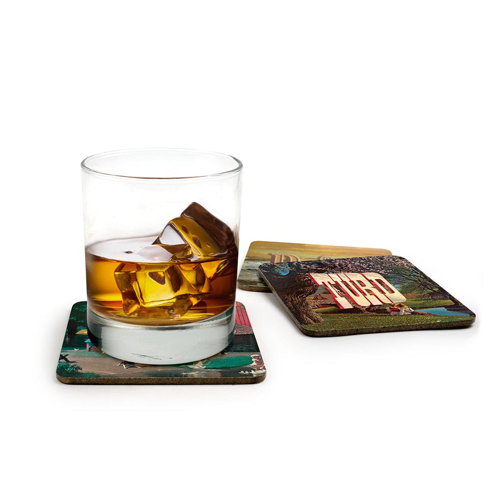 A whiskey drink on top of coasters with art by Wayne White