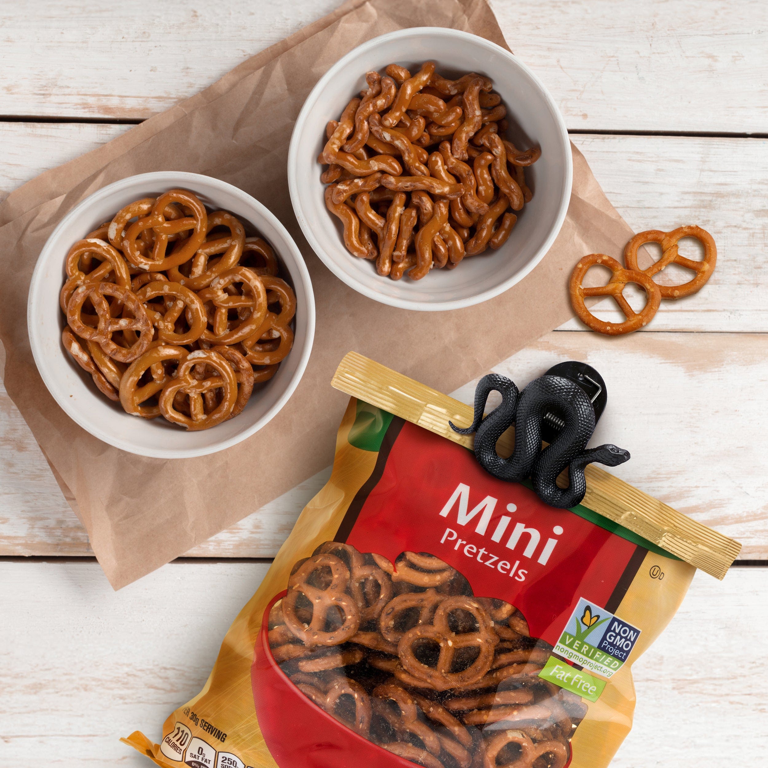 Two bowls of mini pretzels with a package labeled 'Mini Pretzels' clipped with a snake shaped bag clip