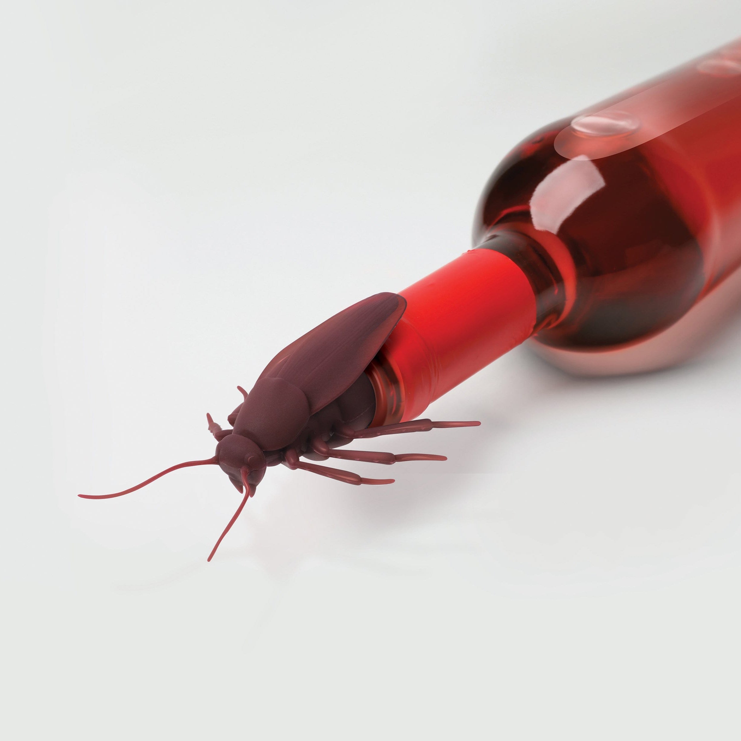 Red bottle with a cockroach bottle stopper on a white background