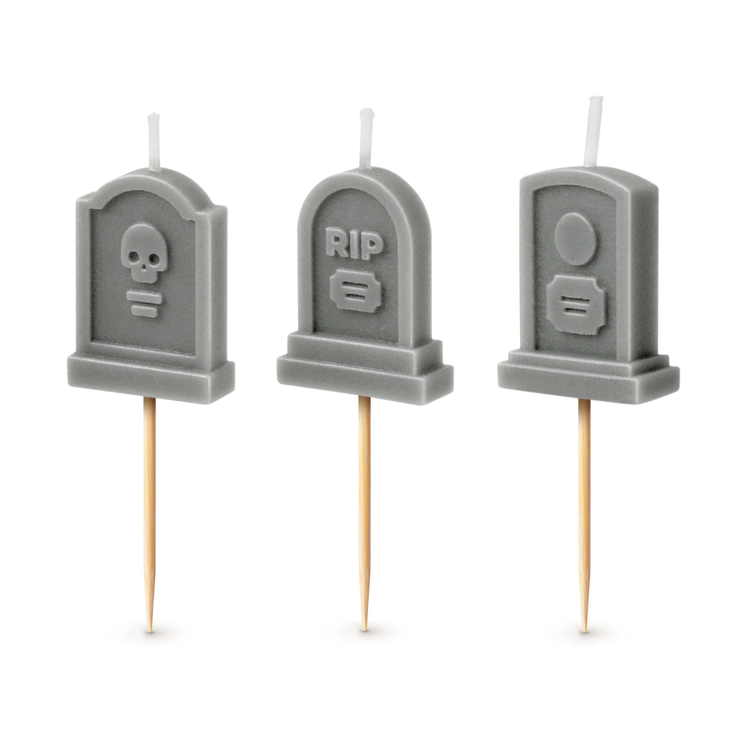 Three gray tombstone-shaped candles with various designs on a white background.