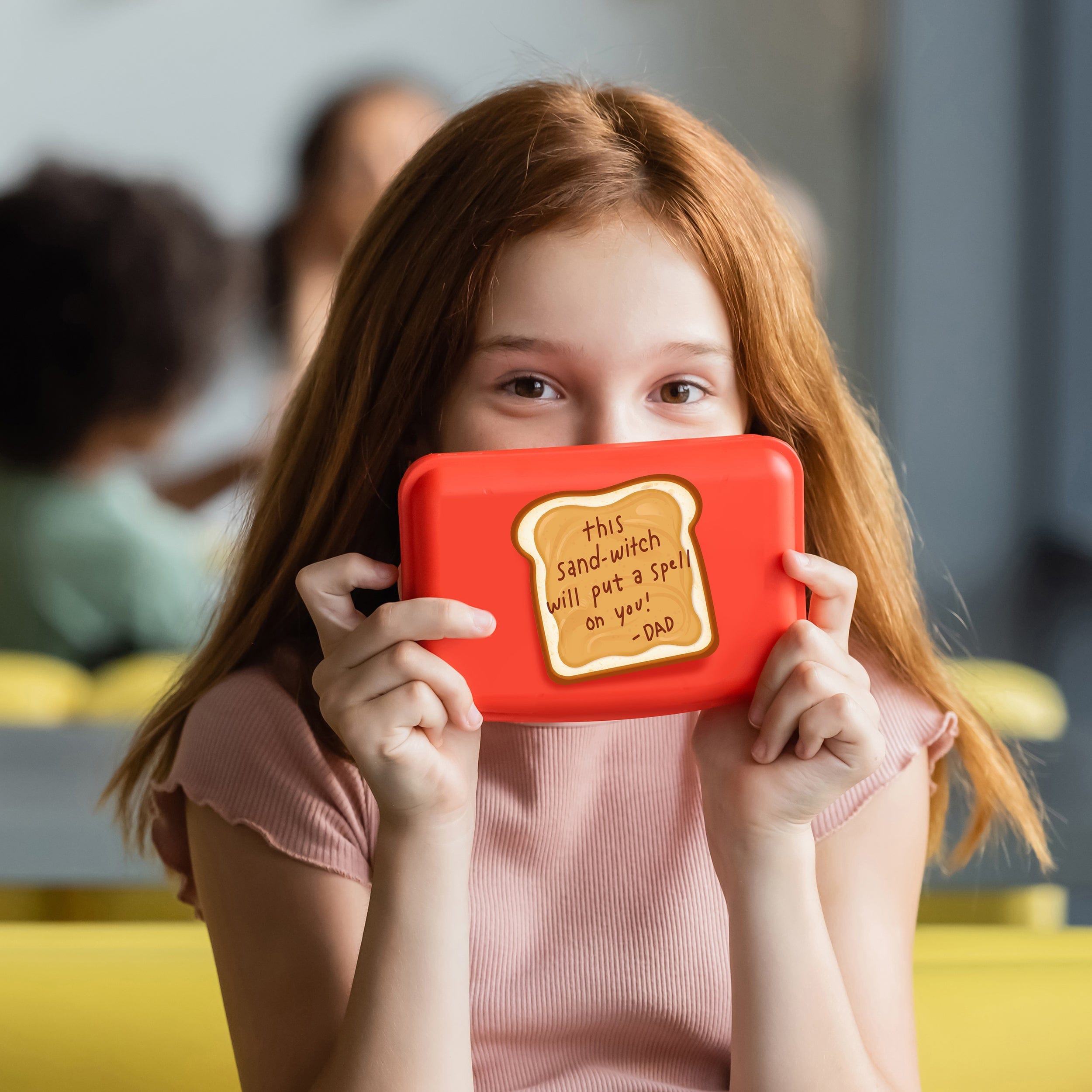 Girl holding a red box with a humorous message on it, blurred background