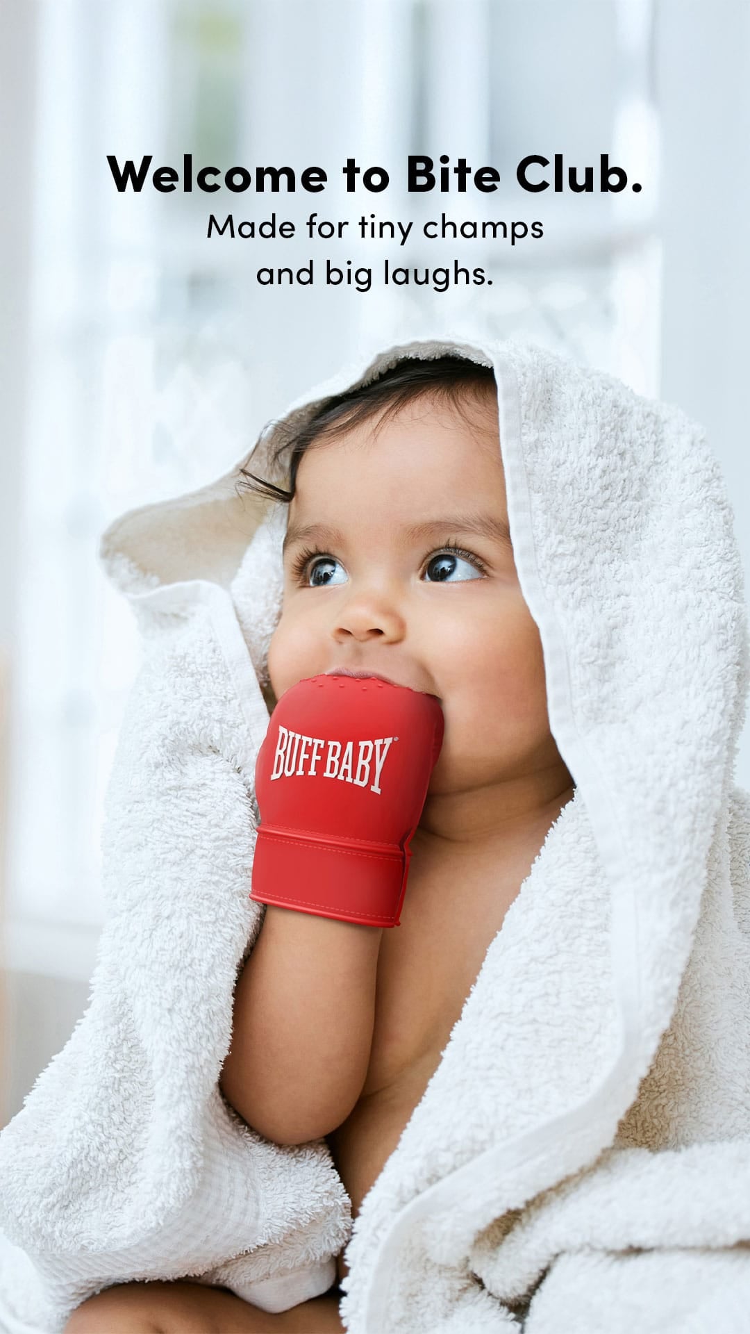 Child wearing red 'Buff Baby' boxing teething glove with a white blanket and text about Bite Club.