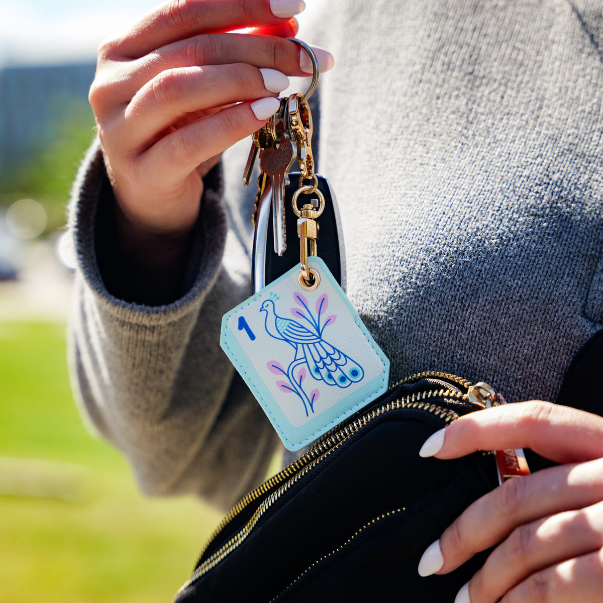 Person holding the Mahjong bird tile bag charm, showing its compact size and functional design. A top-rated practical stocking stuffer and fun holiday gift for tabletop gamers.