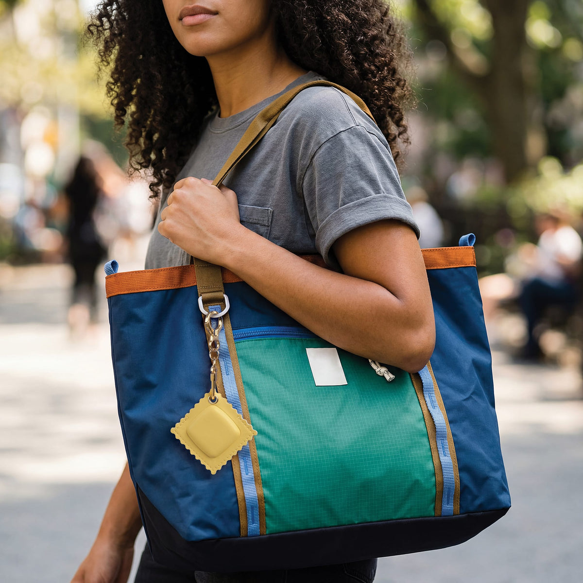 Person holding the ravioli-shaped vegan leather bag charm outdoors. A fun, novelty holiday gift and practical everyday carry item for $10 and under.