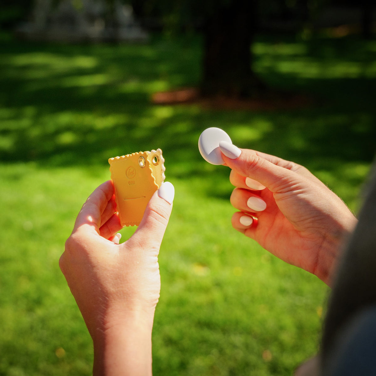 Hands opening the hidden pocket of the ravioli bag charm to reveal a green Apple AirTag®. A clever, budget-friendly tech accessory holiday gift and easy stocking stuffer.